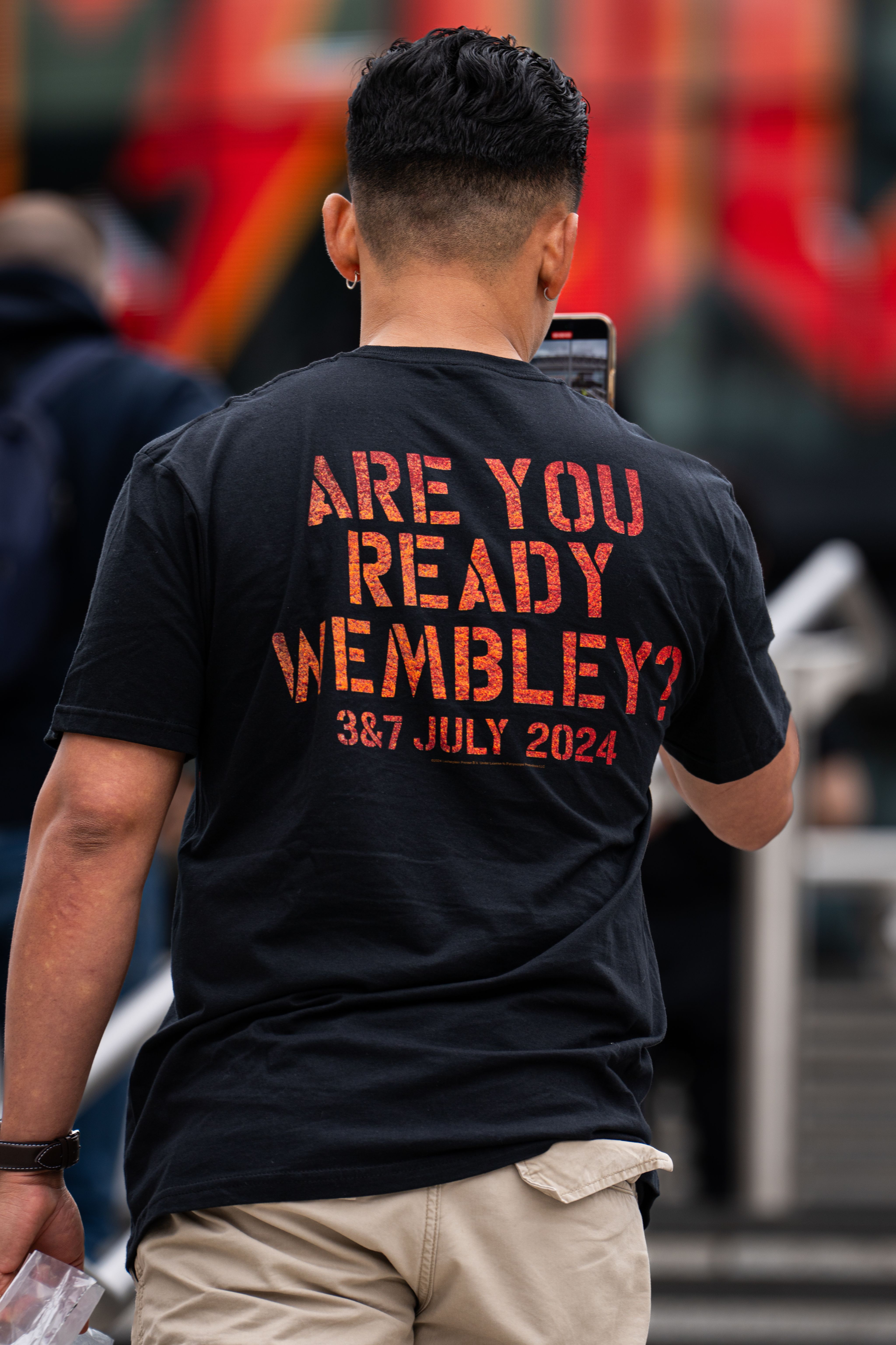 An AC/DC fan poses with a 'ARE YOU READY WEMBLEY' tour t-shirt