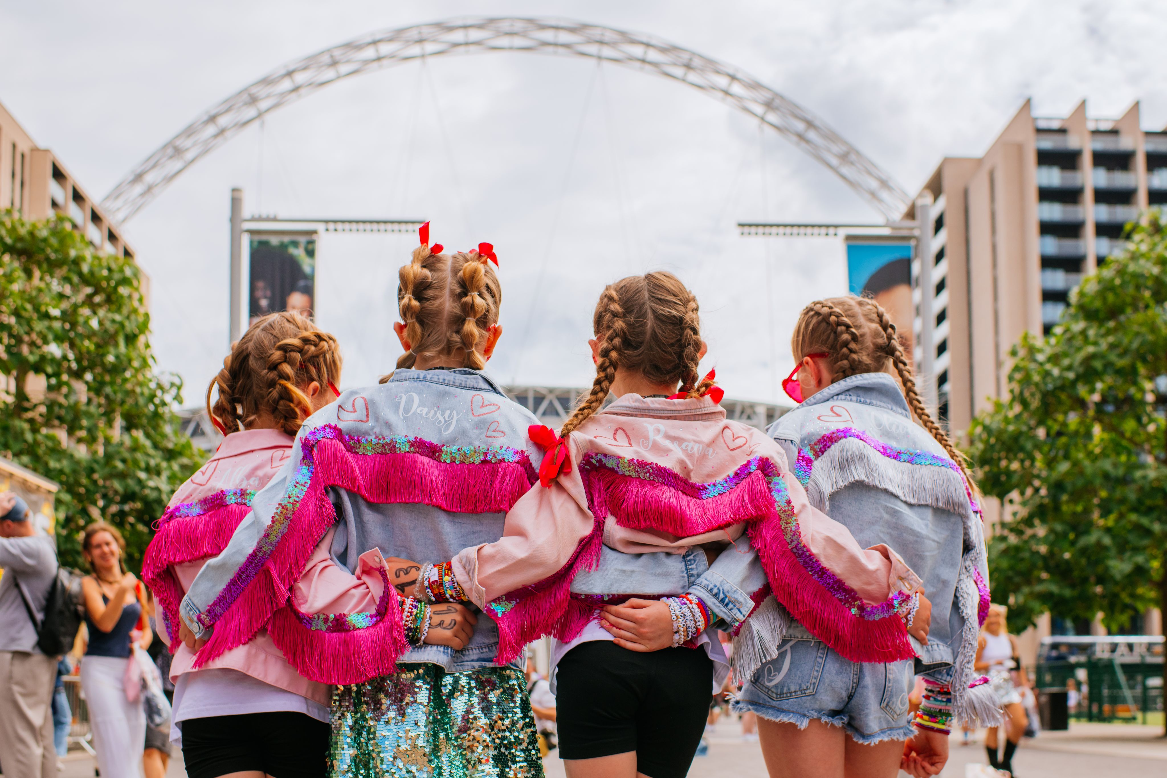 Taylor Swift fans pose arm in arm as they look up at the iconic arch