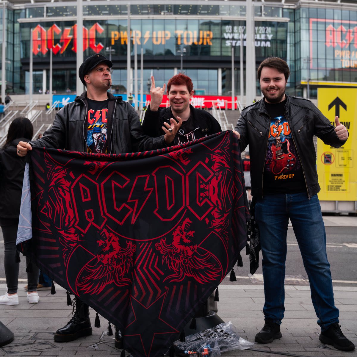 AC/DC fans pose on Wembley Way with an AC/DC flag