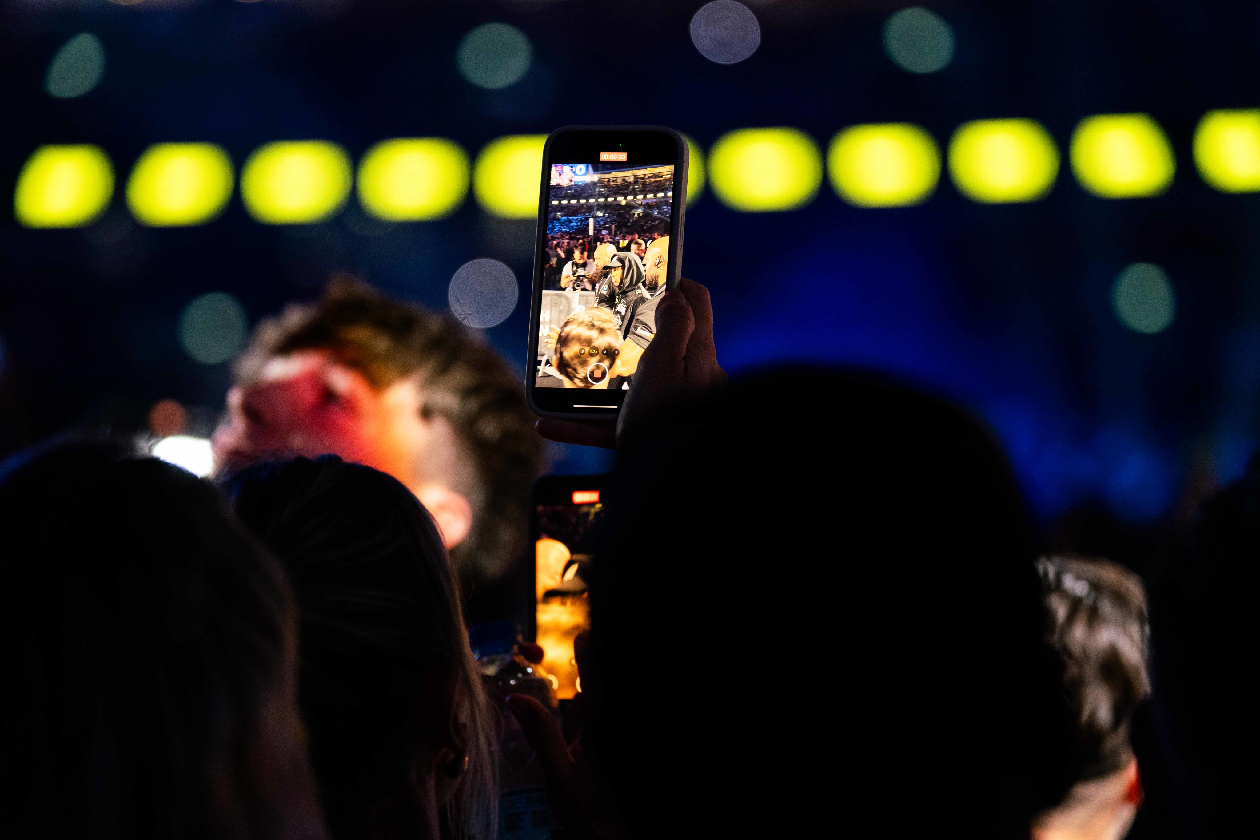 A supporter records a video on their phone inside the stadium during the build up